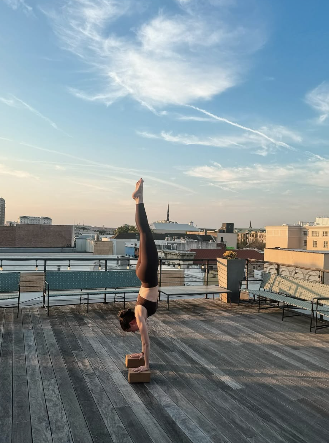 Kiley Phelan holding a handstand on a rooftop at sunset